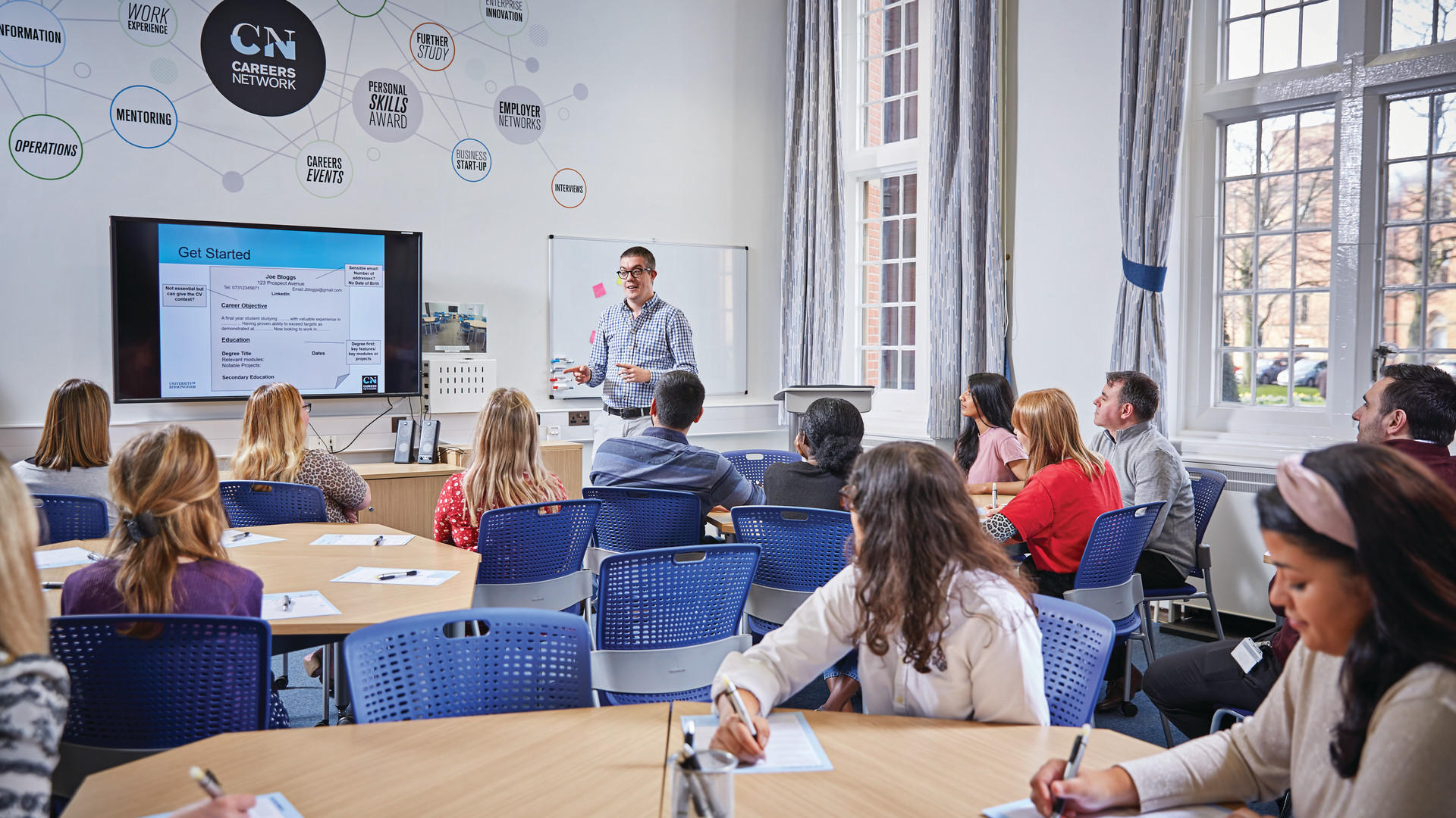 Students sit at tables listening t a presentation