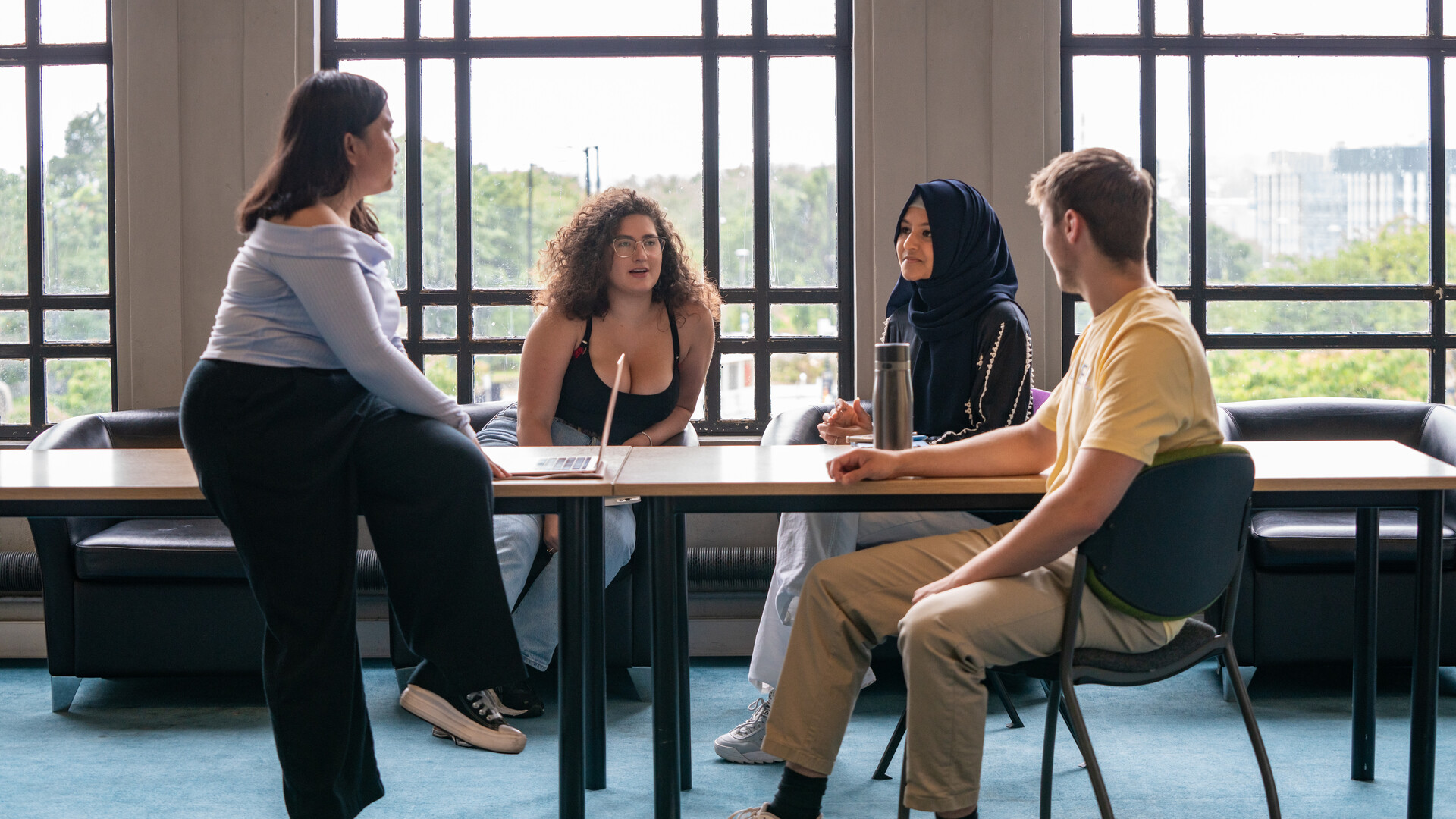 A group of students sit around a table chatting