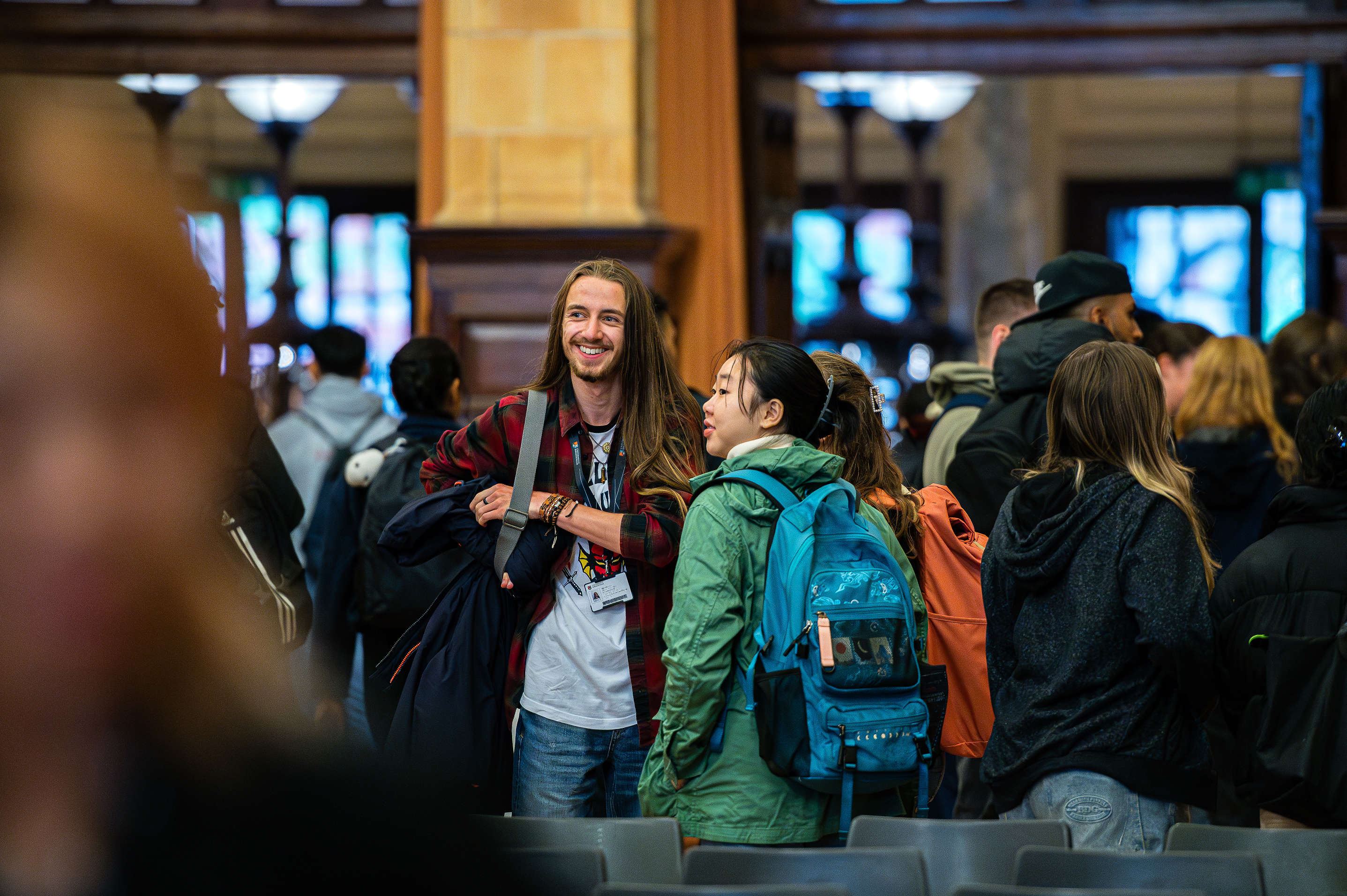 Two students in conversation in the crowded Great Hall